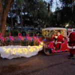 Santa on golf cart sled pulled by 9 flying pink flamingos with antlers, one with a glowing red nose, at the Lakes at Leesburg annual golf cart parade